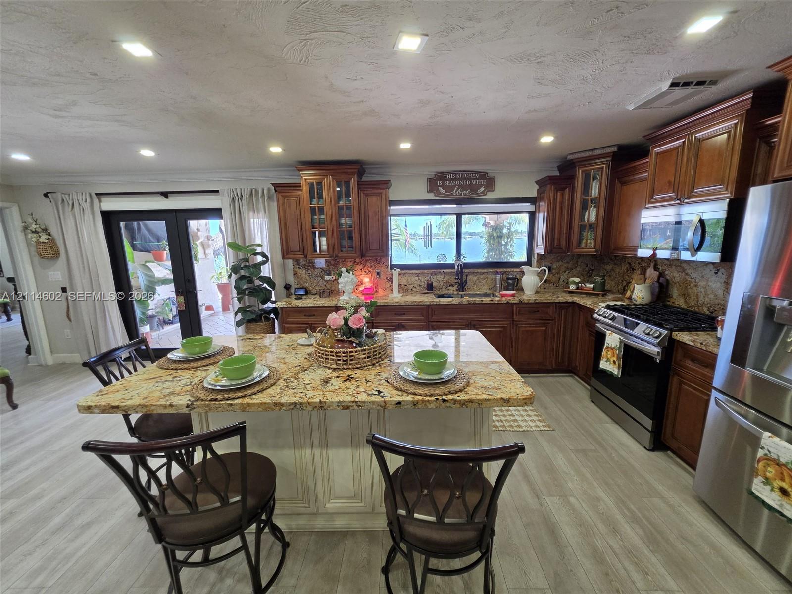 Kitchen featuring stained wood cabinetry, stone countertops, a central island with integrated seating space, recessed lighting, and stainless steel appliances