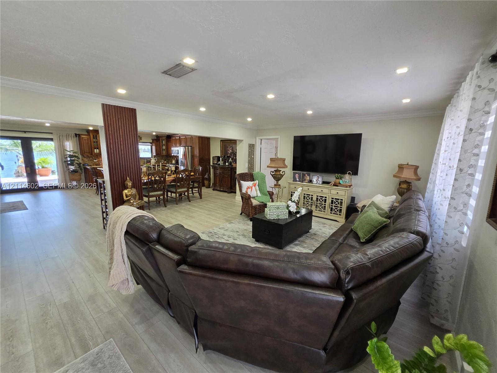 Open concept floor plan featuring recessed lighting, wood-finish flooring, decorative vertical pillar detailing, and double French doors