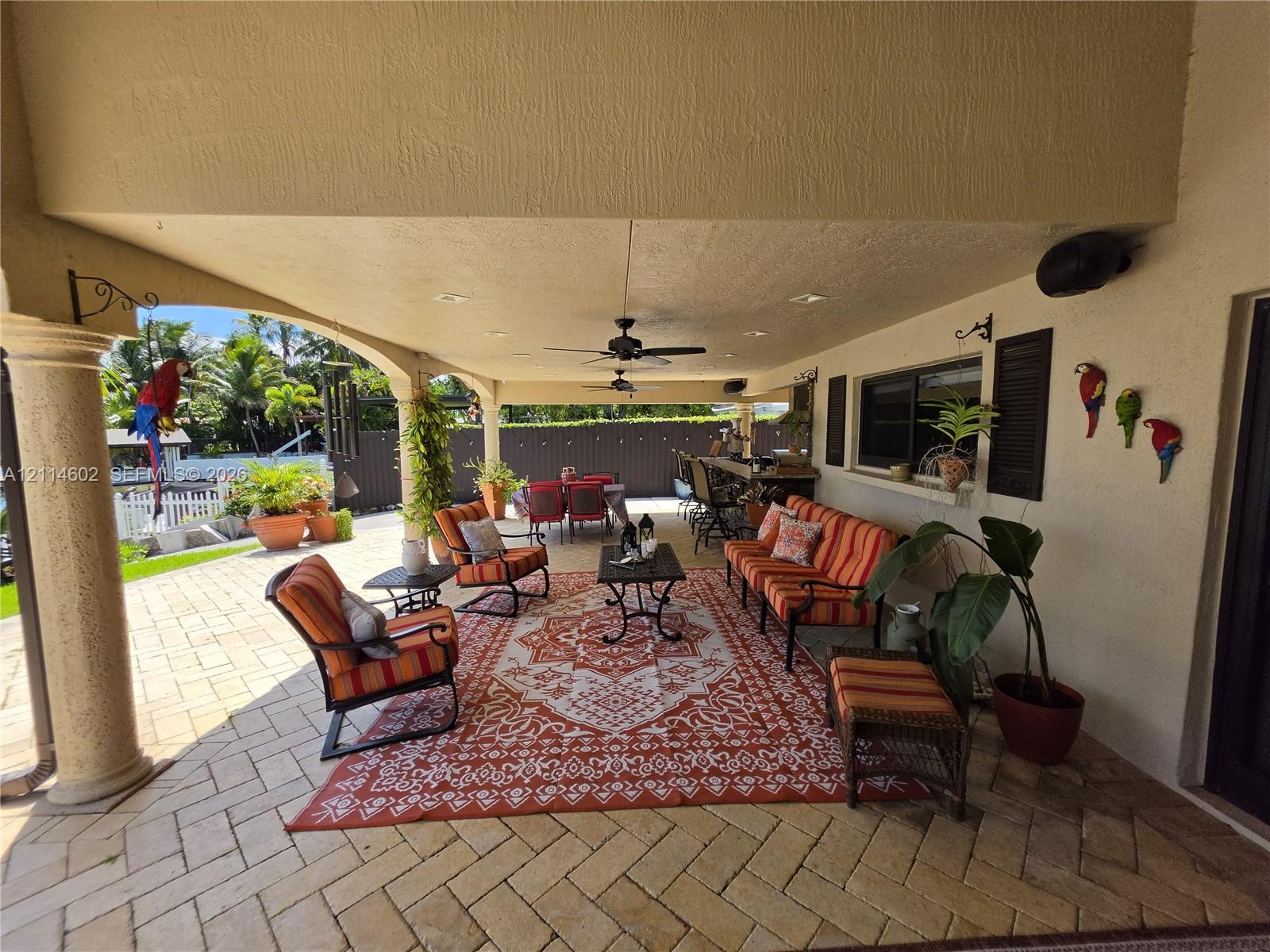 Covered patio featuring herringbone-pattern paver flooring, recessed lighting, ceiling fans, and an arched architectural column