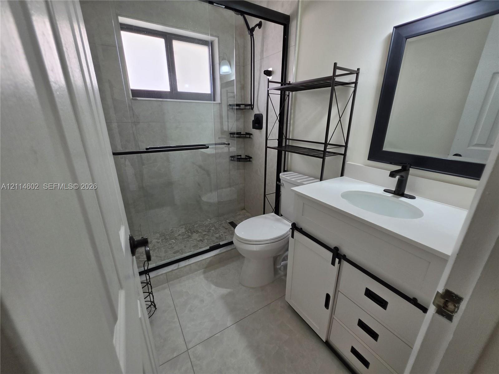 White vanity with a rectangular sink, matte black hardware, and an integrated countertop