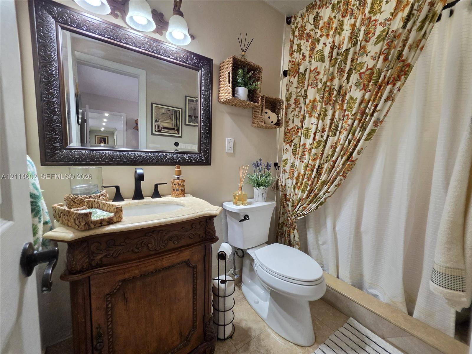 Carved wooden vanity featuring an integrated basin and countertop, ornate framed wall mirror, and three-light decorative fixture