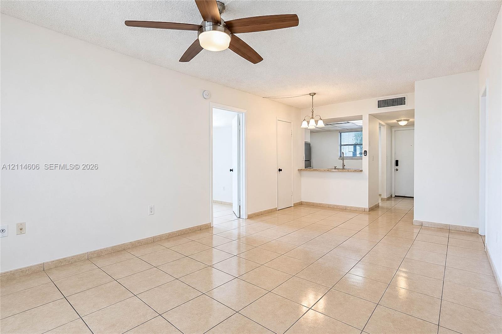 Neutral-toned tile flooring, ceiling fan with integrated lighting, built-in breakfast bar, and multi-light chandelier fixture Neutral-toned tile flooring, ceiling fan with integrated lighting, built-in breakfast bar, and multi-light chandelier fixture