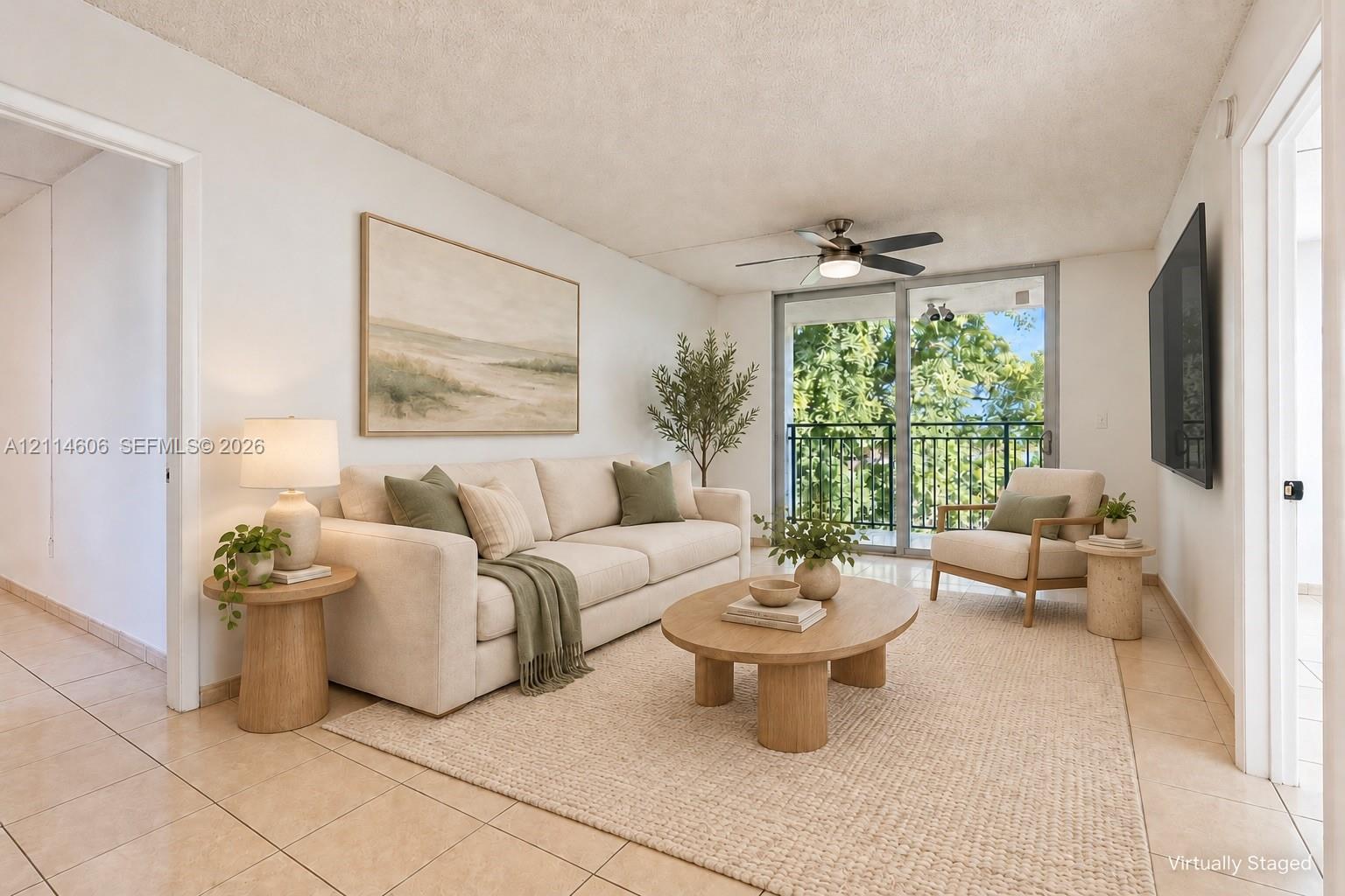 Living area featuring large-format tile flooring, a ceiling fan with integrated lighting, and a sliding glass door providing access to a private balcony with metal railings Living area featuring large-format tile flooring, a ceiling fan with integrated lighting, and a sliding glass door providing access to a private balcony with metal railings