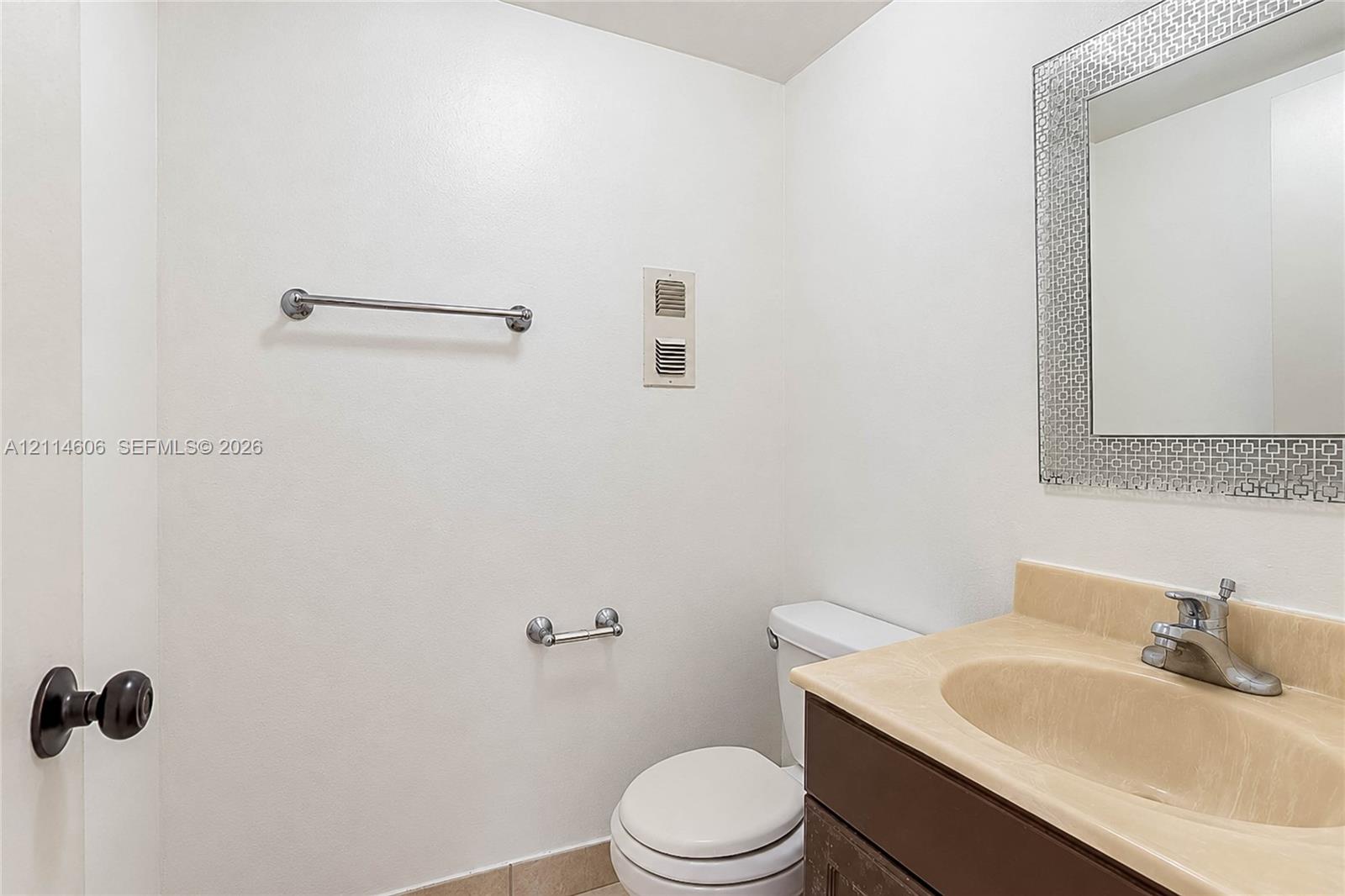 Vanity with a solid-surface countertop and integrated sink, complemented by a decorative framed mirror, dark-finish cabinetry, and polished metal hardware