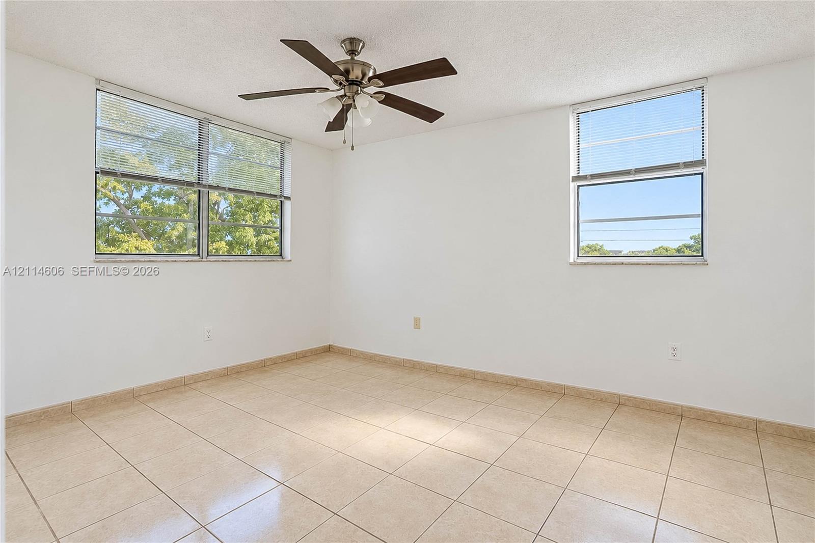 Light-filled room featuring neutral tile flooring, multi-pane windows, and a ceiling fan with integrated lighting