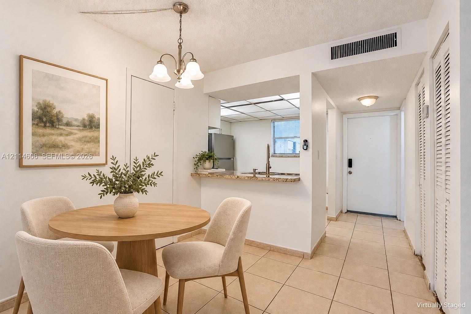 Kitchen area featuring a stone-surface breakfast bar, ceramic tile flooring, a suspended three-light chandelier, and louvered-door closets Kitchen area featuring a stone-surface breakfast bar, ceramic tile flooring, a suspended three-light chandelier, and louvered-door closets