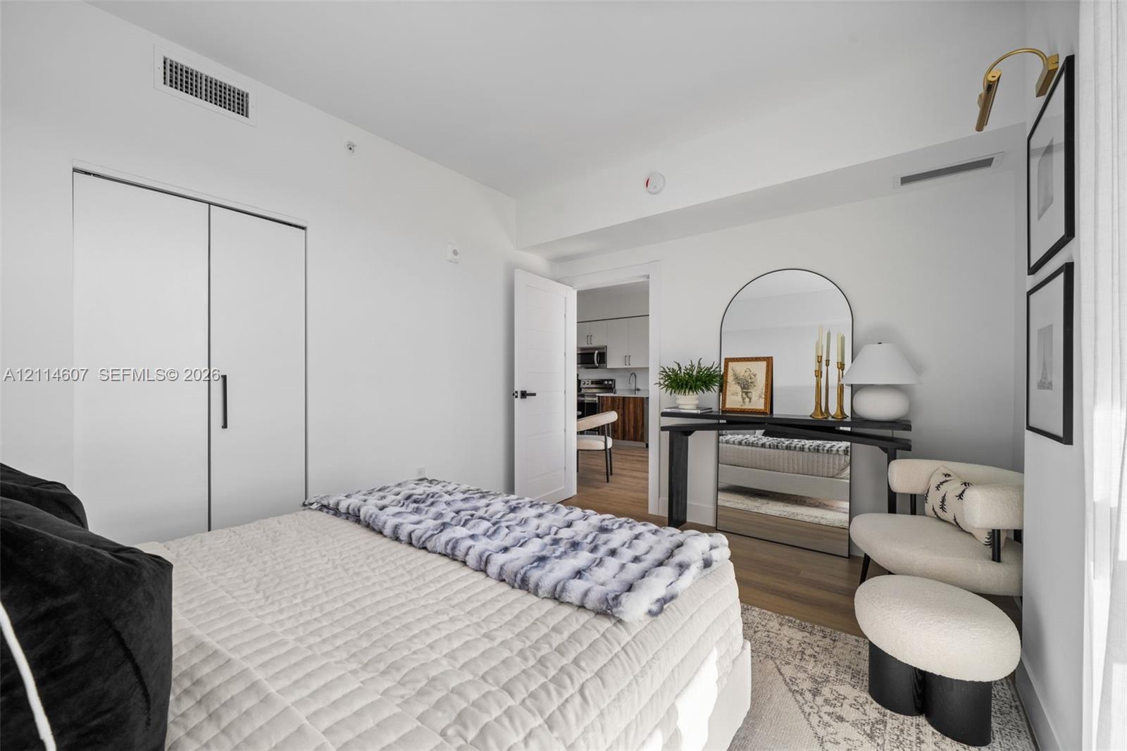 Room featuring wood-finish flooring, white walls, and a closet with black hardware