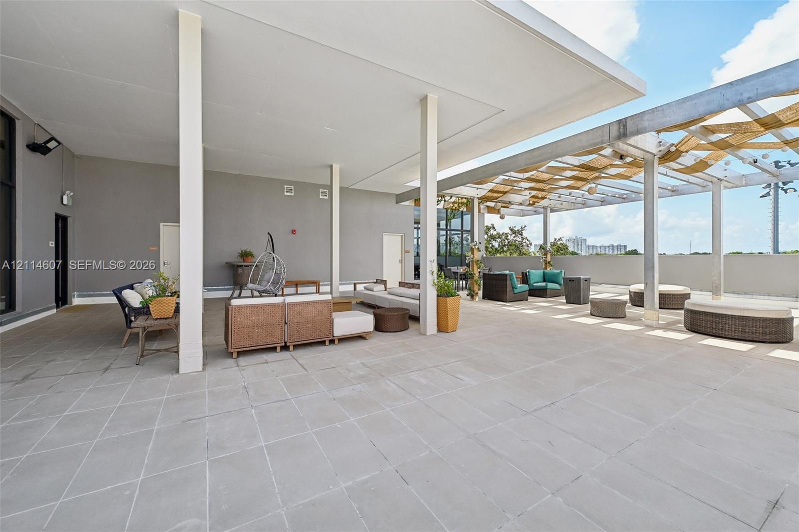 Expansive rooftop terrace featuring large-format stone tile flooring, a covered patio section with structural support columns, and an open-air area with a metal pergola frame