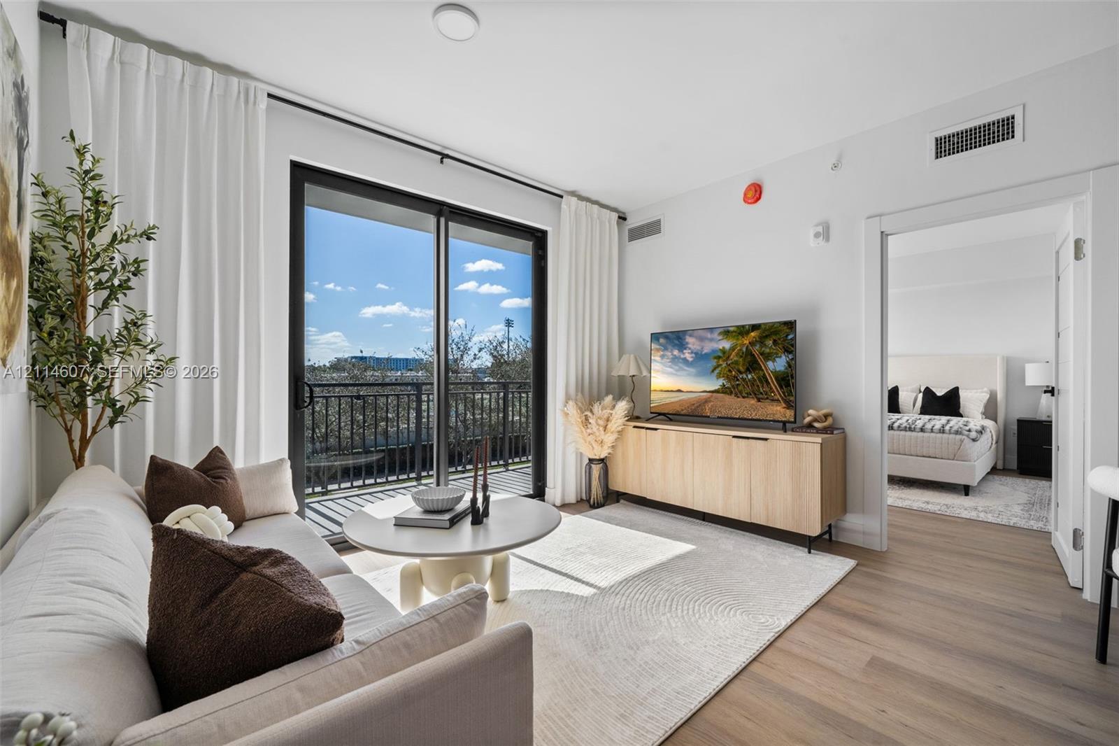 Living area featuring wood-finish flooring, sliding glass doors, and a metal balcony railing
