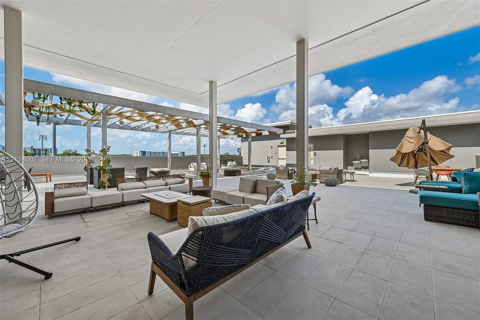 Expansive rooftop terrace featuring large-format stone tile flooring, an oversized covered patio area, and an integrated pergola structure