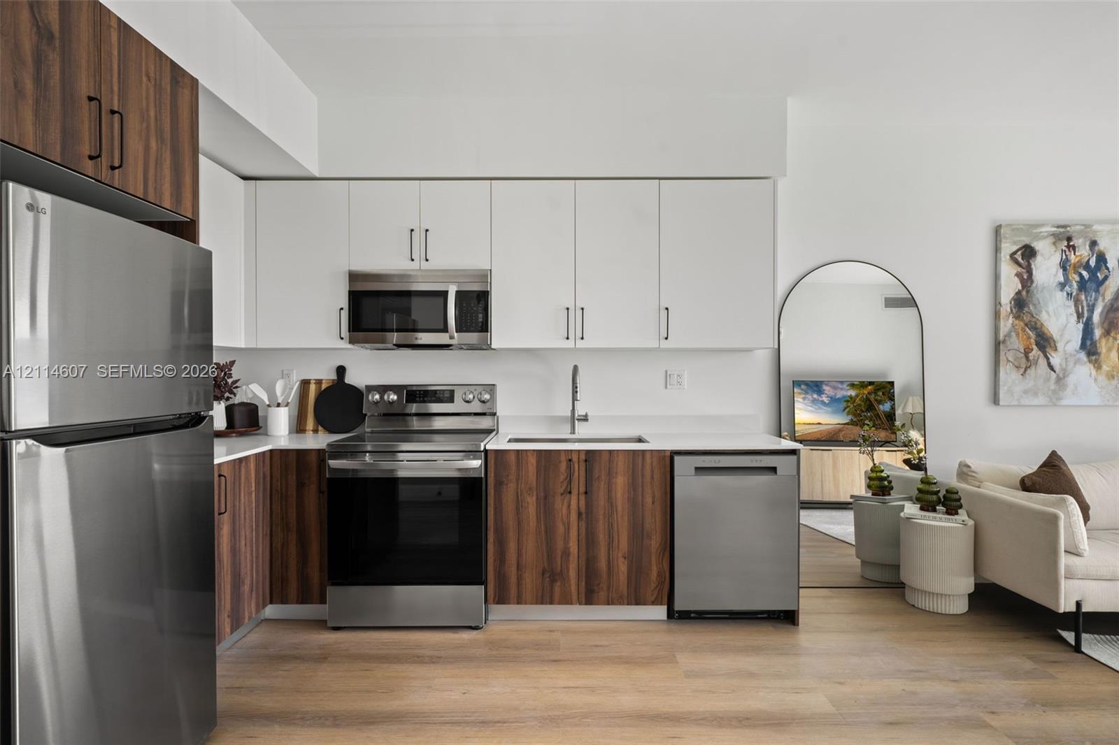 Kitchen featuring two-tone cabinetry with wood-finish lower and solid-color upper doors, stainless steel appliances, and solid-surface countertops