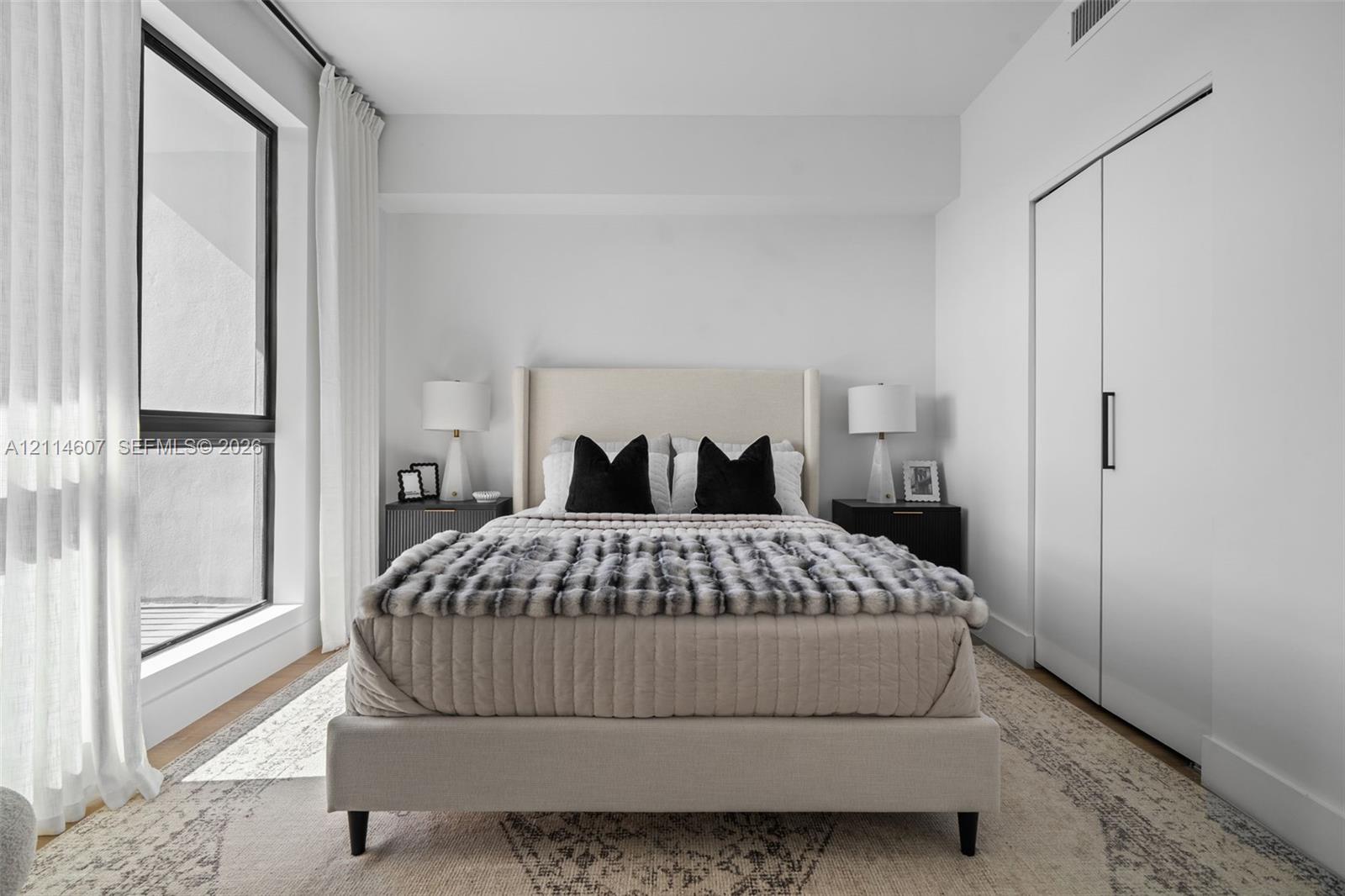 Floor-to-ceiling windows with black frames, wood-finish flooring, and built-in closet with matte black hardware