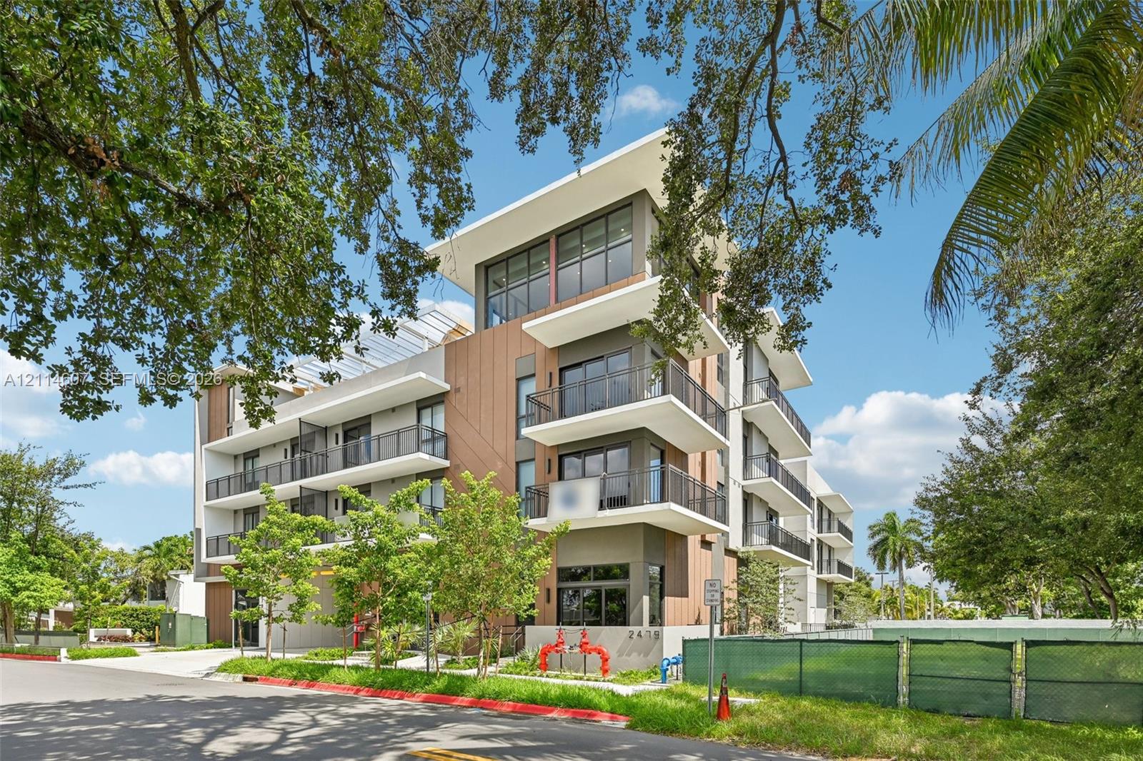 Contemporary multi-story exterior featuring vertical wood-finish siding, white structural cantilevered balconies, metal railings, and expansive glass window walls