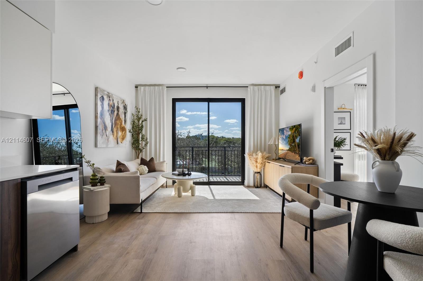 Open-concept living space featuring wood-finish flooring, sliding glass doors, and a private balcony
