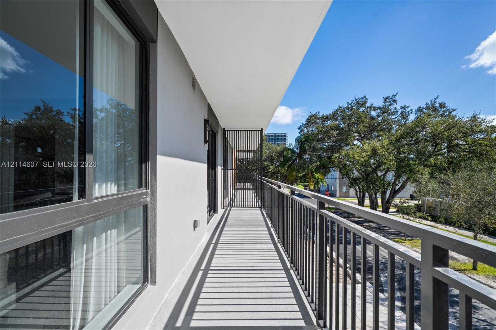 Private balcony featuring metal railing, vertical privacy screen, and neutral concrete flooring