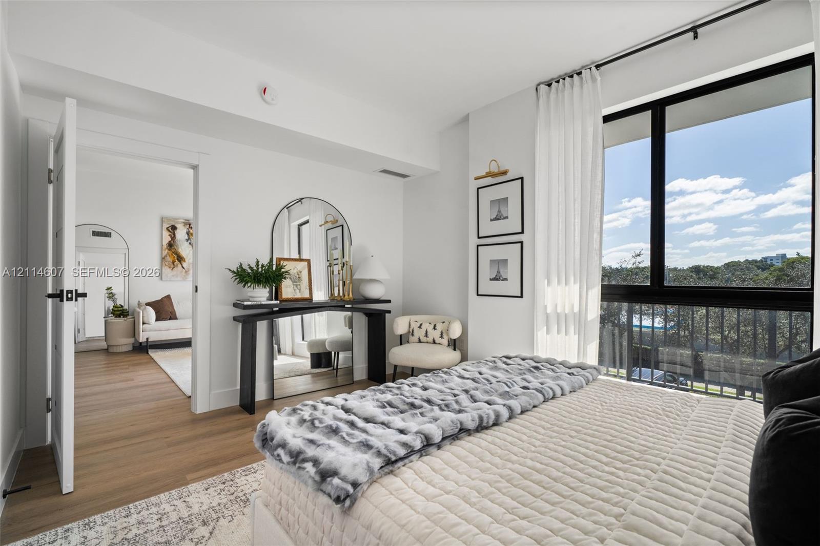 Interior space featuring wood-finish flooring, floor-to-ceiling windows with black framing, and a metal balcony railing