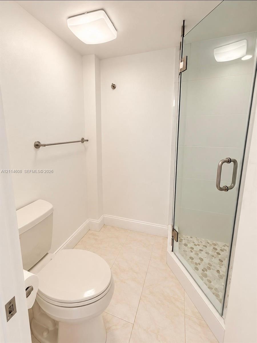 Bathroom featuring a glass-enclosed shower with pebble-stone flooring