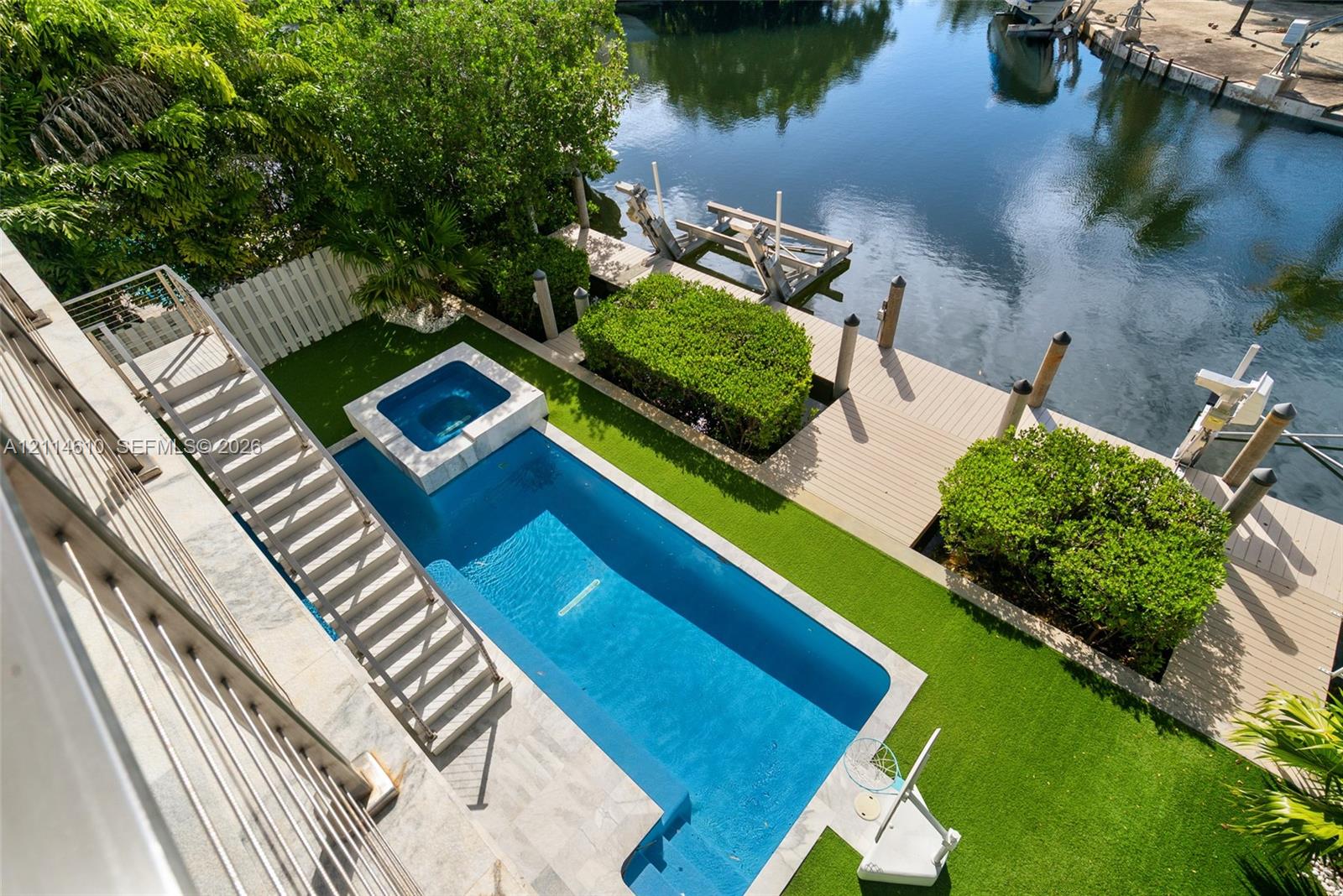 Waterfront patio featuring a private swimming pool with integrated spa, composite decking, artificial turf, and a private boat dock