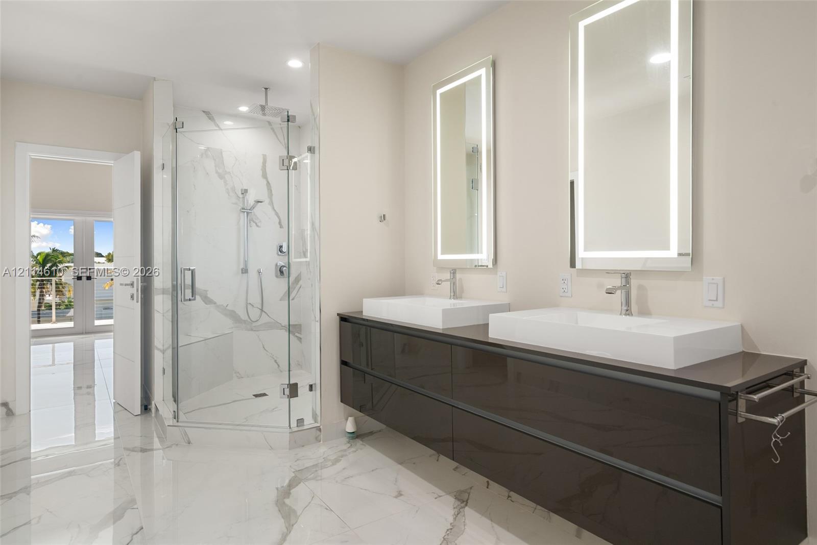 Floating dual vanity with vessel sinks, stone-finish flooring, glass-enclosed walk-in shower with stone-finish wall tile, and backlit vanity mirrors