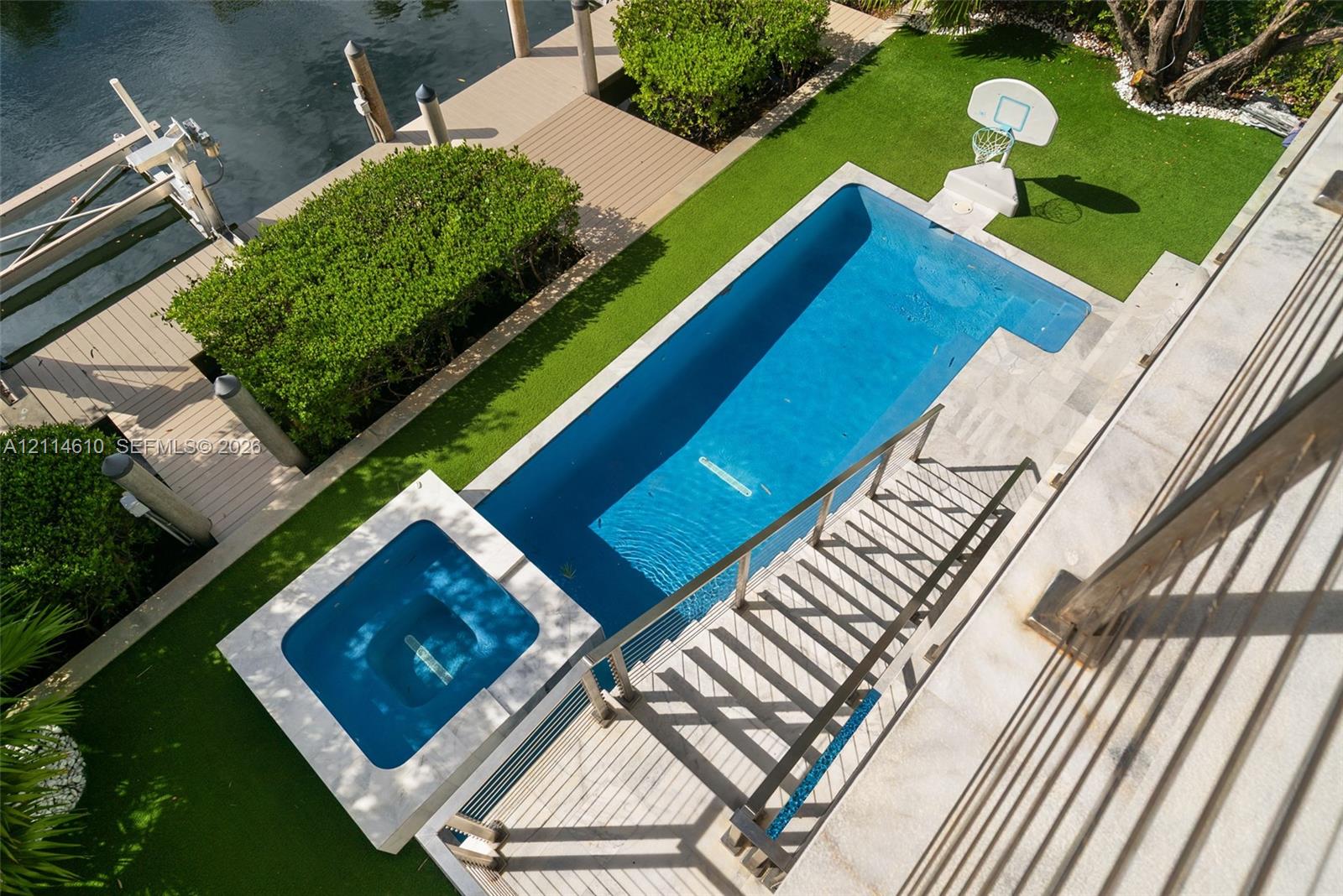 Waterfront property featuring a custom in-ground swimming pool, integrated spa, synthetic turf lawn, and a private composite dock