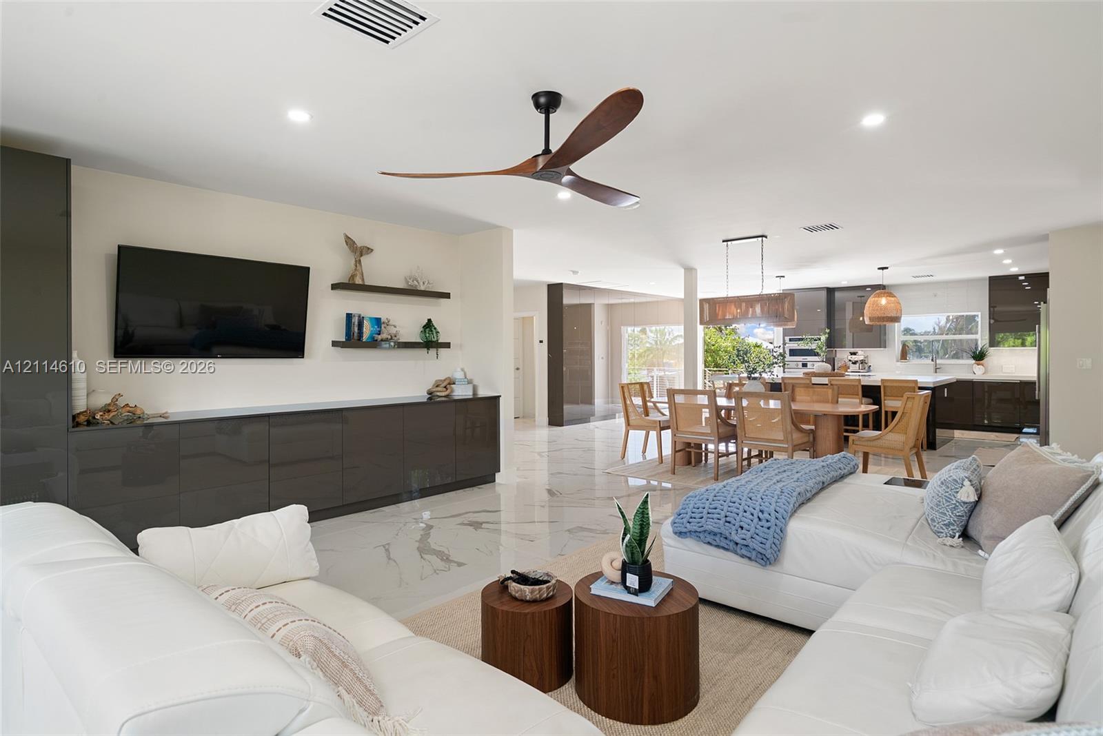 High-gloss cabinetry, large-format stone-finish flooring, recessed lighting, sculptural ceiling fan, and floating wall shelves