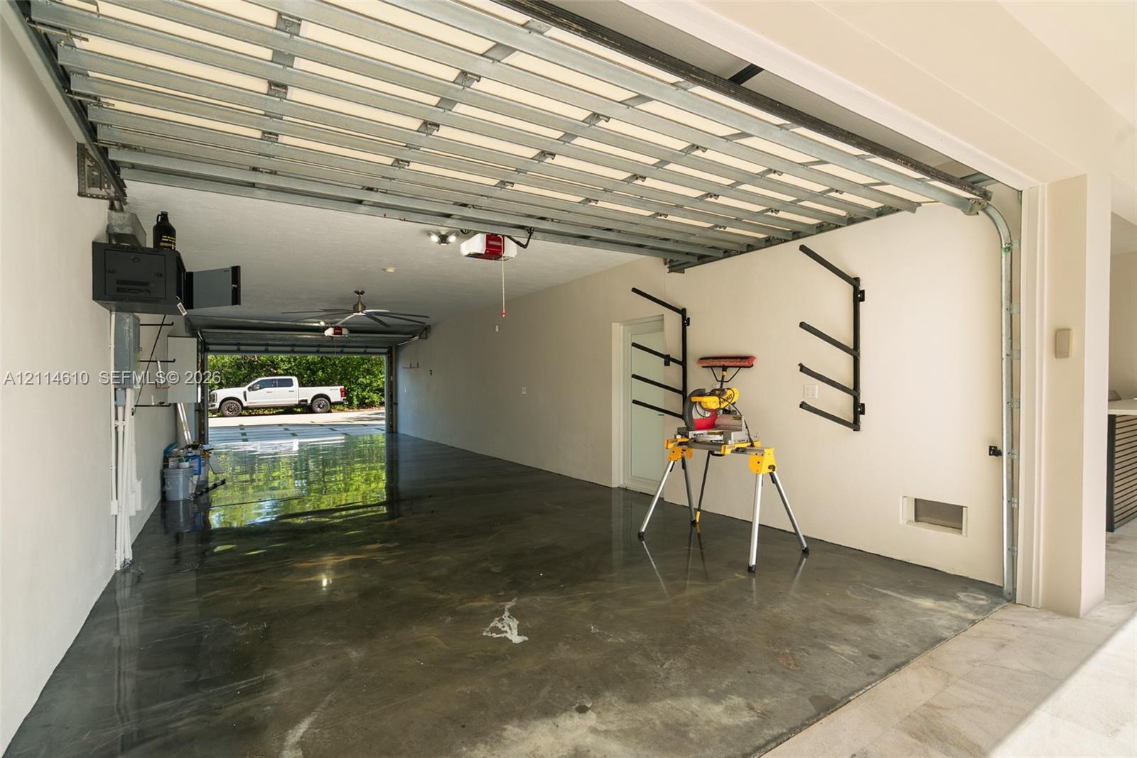 Attached garage featuring epoxy-coated flooring, dual-door access, ceiling-mounted lighting, and wall-mounted storage racks