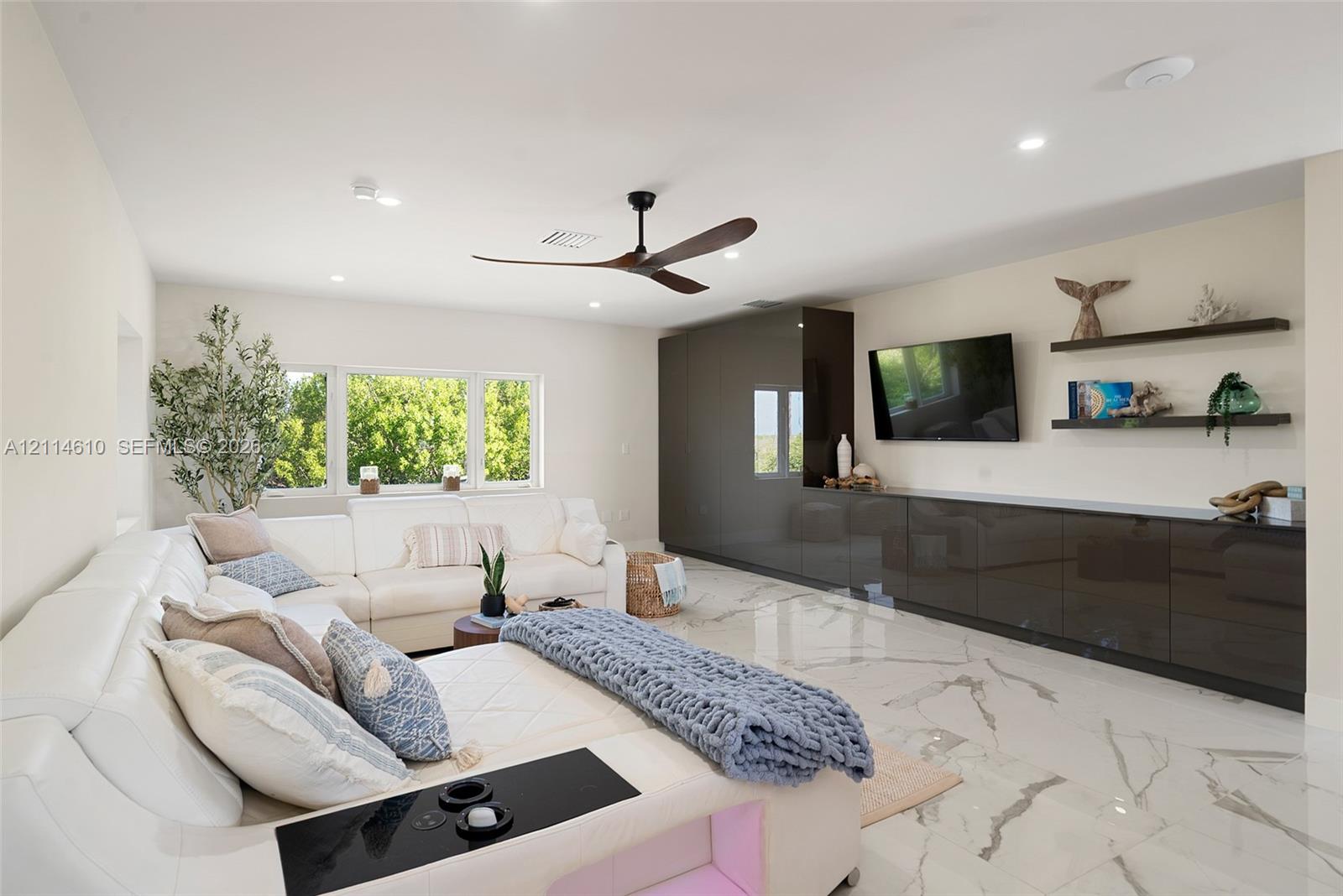 Large-format tile flooring, high-gloss built-in cabinetry, recessed lighting, multi-blade ceiling fan, and floating wall shelves