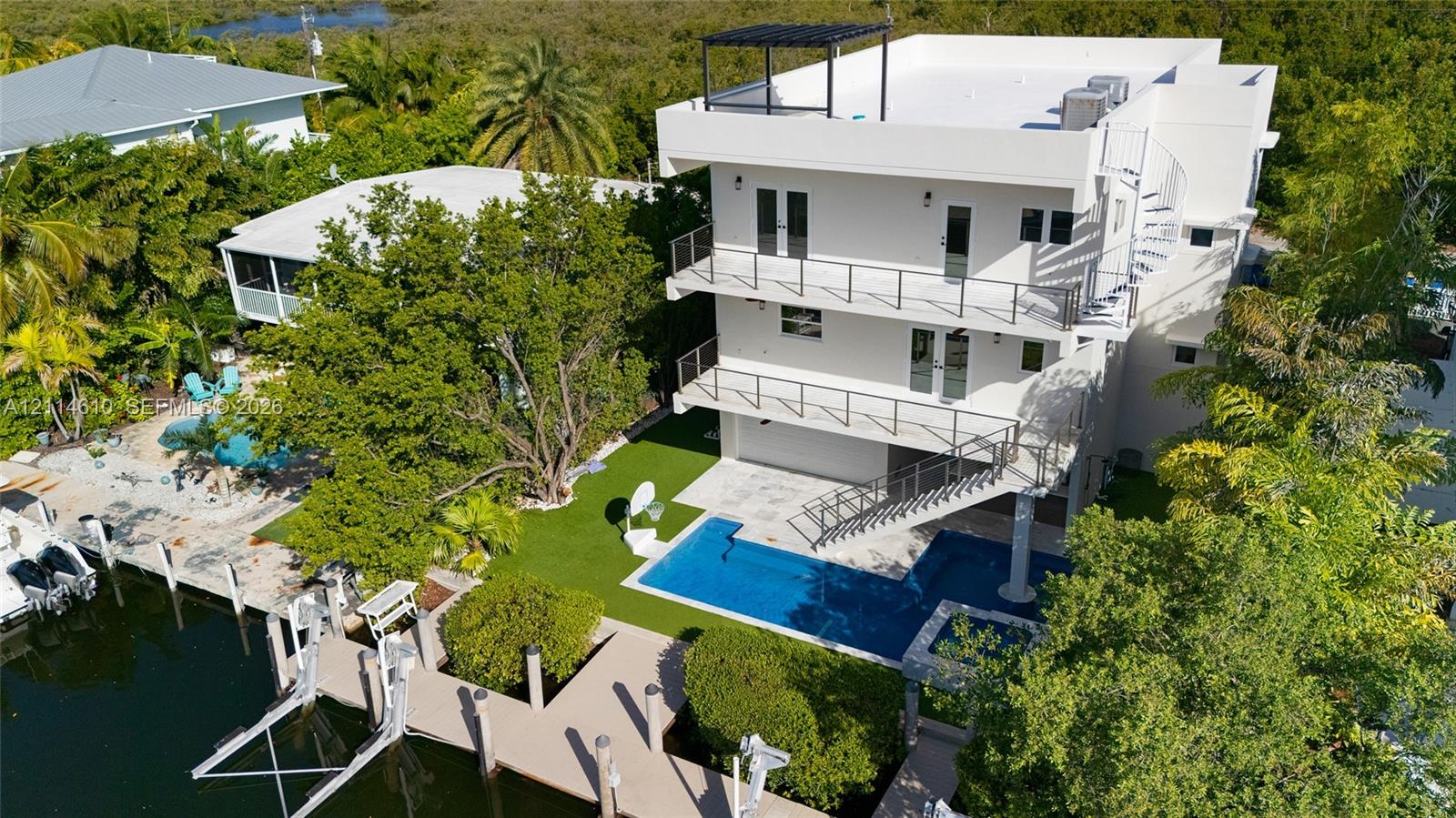 Three-story waterfront residence featuring multi-level balconies, a private boat dock, an in-ground swimming pool, and a rooftop deck