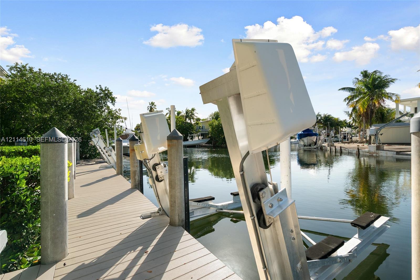 Private dock featuring synthetic wood-finish decking, pilings with caps, and multiple integrated boat lifts