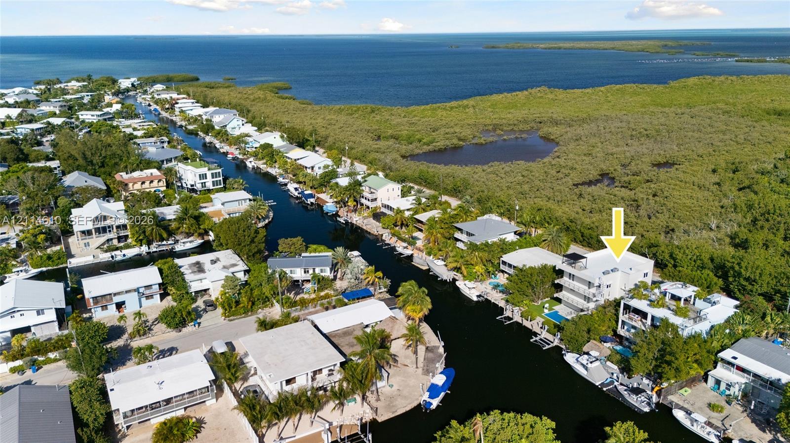 Waterfront property featuring a canal-side bulkhead, multi-level balconies, a private swimming pool, and flat roof design