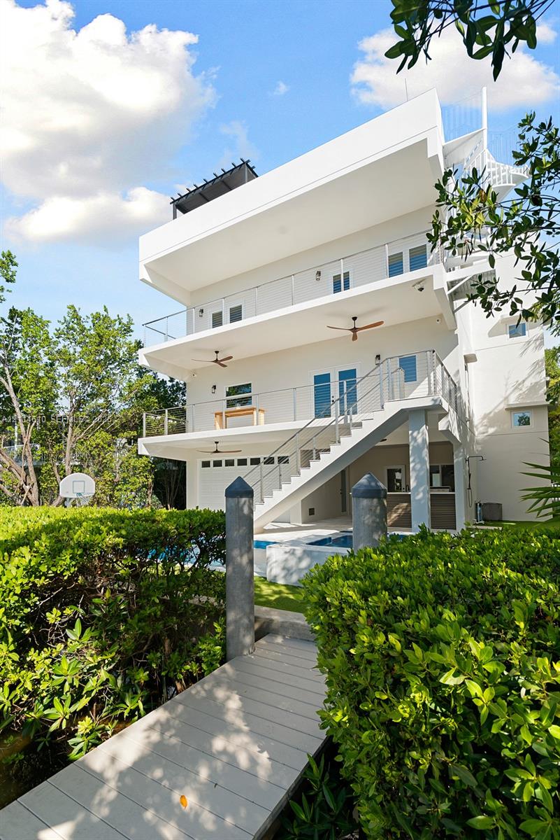 Multi-story exterior featuring stacked balconies with glass railings, an integrated swimming pool, a private dock with pilings, and an external staircase