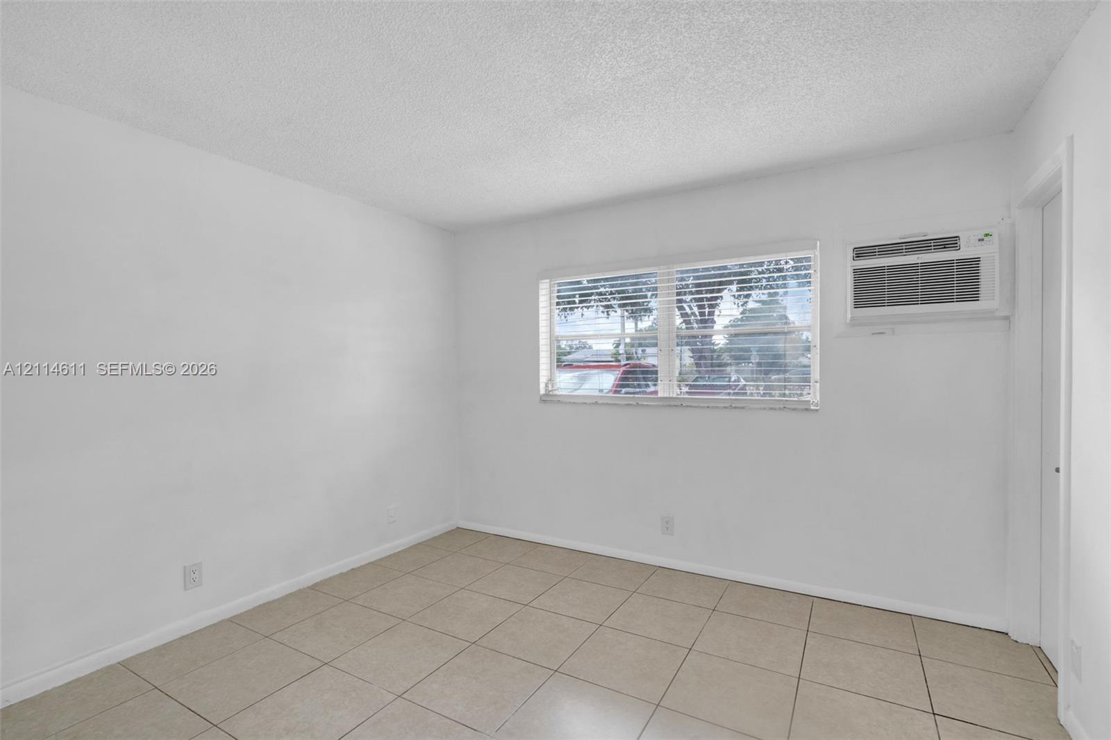Interior space featuring ceramic tile flooring, neutral walls, and a wall-mounted air conditioning unit