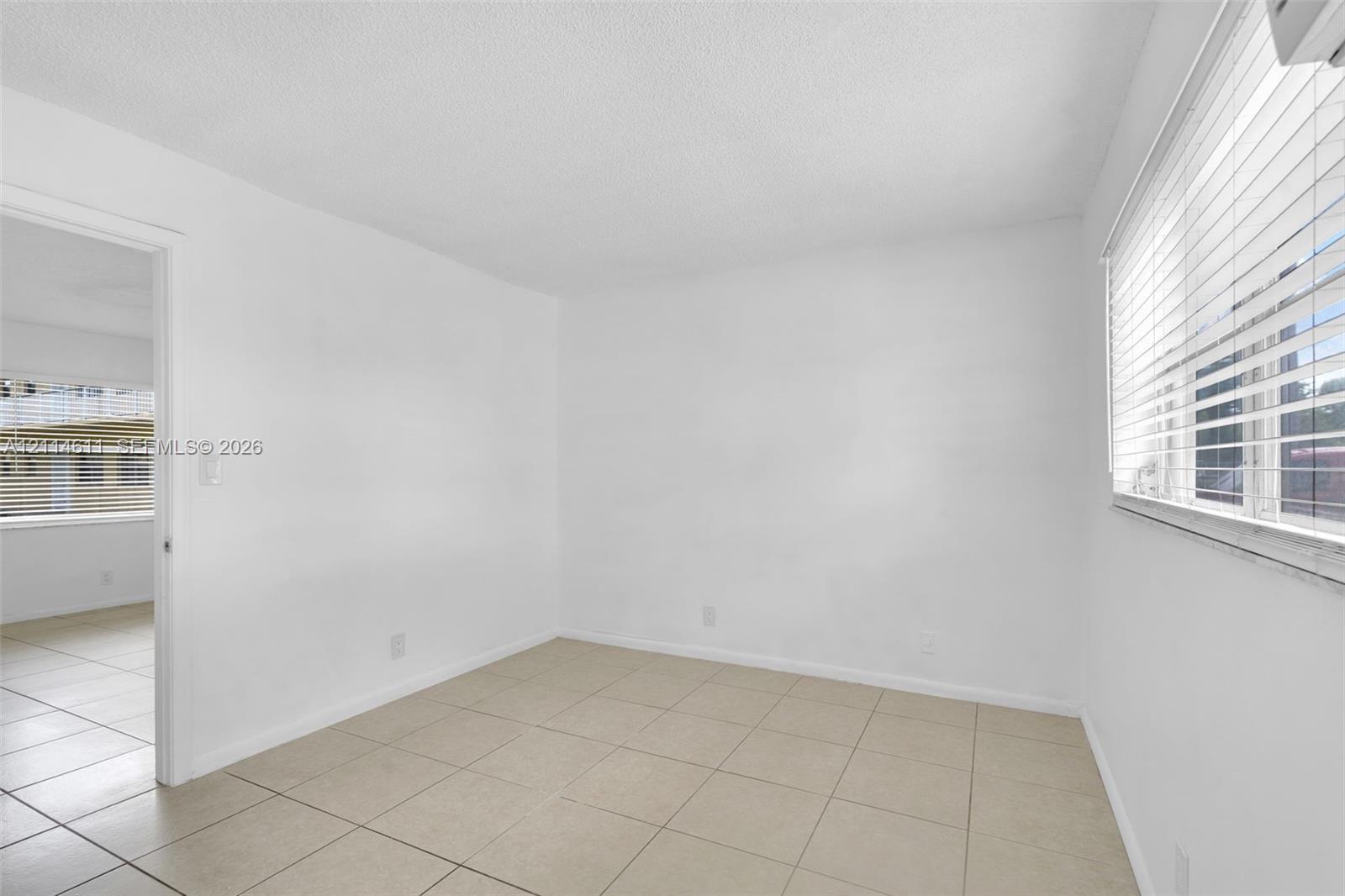 Neutral-toned tile flooring, horizontal window blinds, and solid white wall finishes
