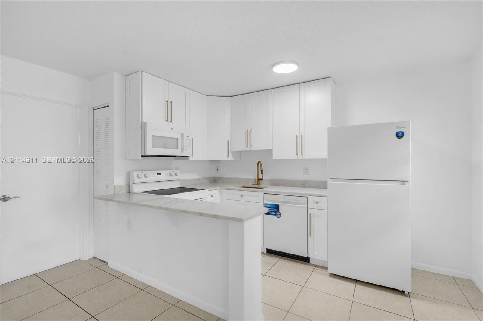 Kitchen featuring white cabinetry with metallic hardware, stone-finish countertops, tile flooring, and integrated white appliances Kitchen featuring white cabinetry with metallic hardware, stone-finish countertops, tile flooring, and integrated white appliances