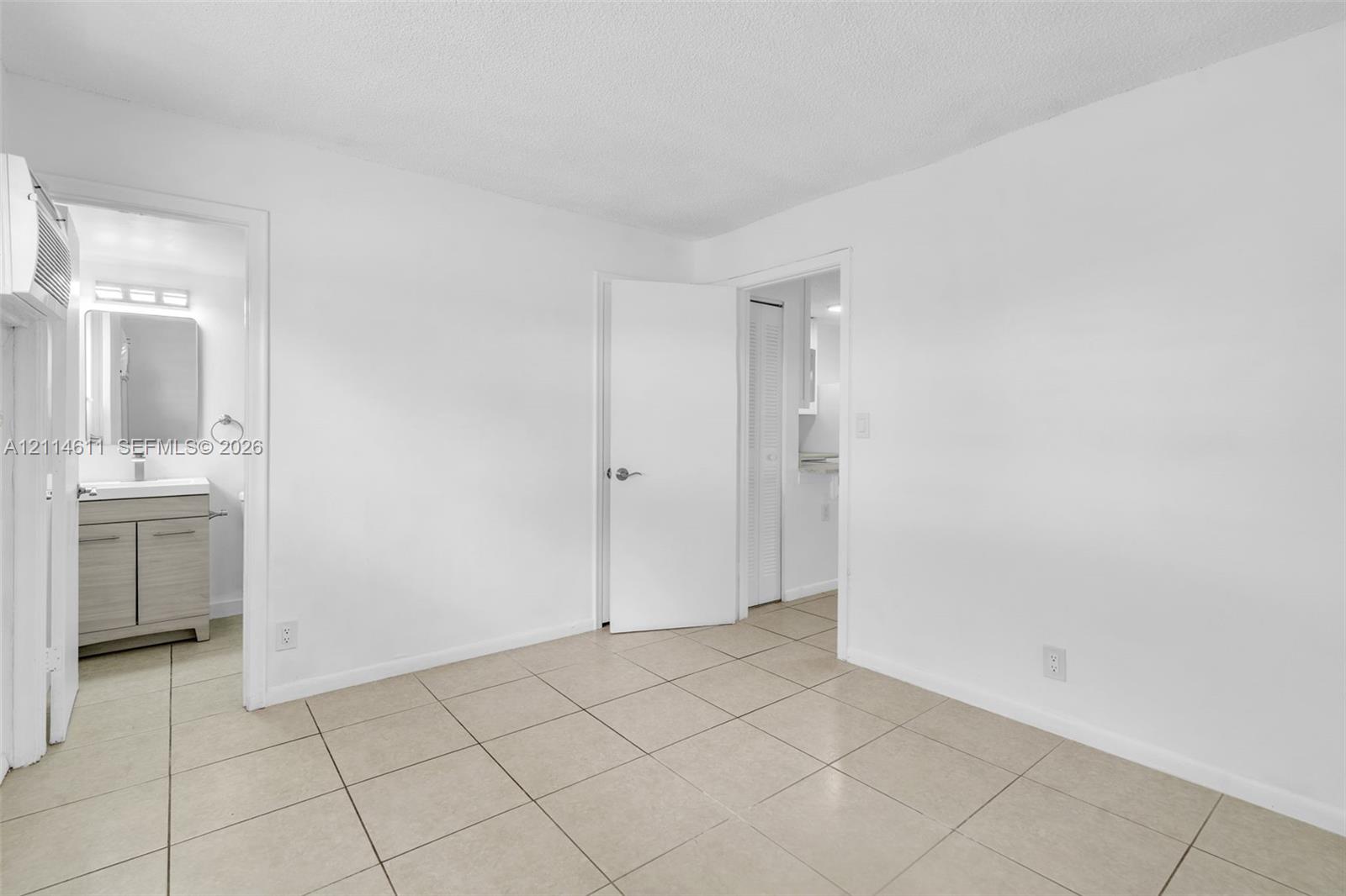 Interior space featuring neutral tile flooring and a vanity with a rectangular sink, stone-finish countertop, and integrated storage cabinetry Interior space featuring neutral tile flooring and a vanity with a rectangular sink, stone-finish countertop, and integrated storage cabinetry