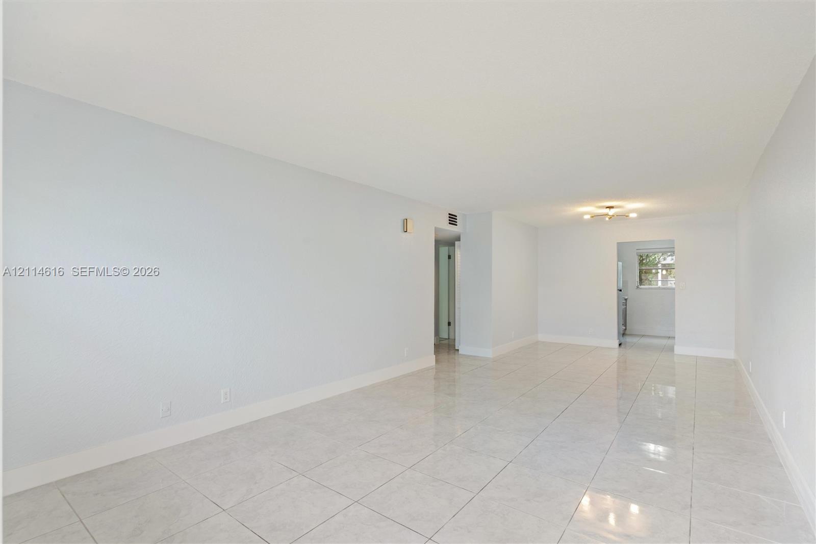 Neutral-toned interior featuring large-format tile flooring and a ceiling-mounted light fixture