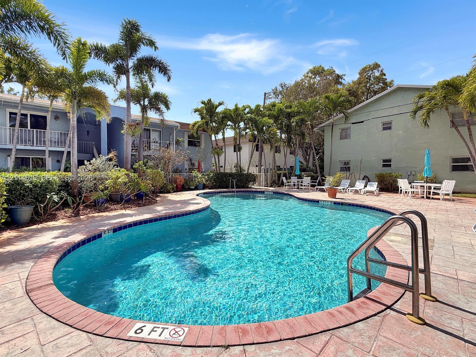 Swimming pool with brick-accented coping, concrete paver decking, and surrounding mature palm trees