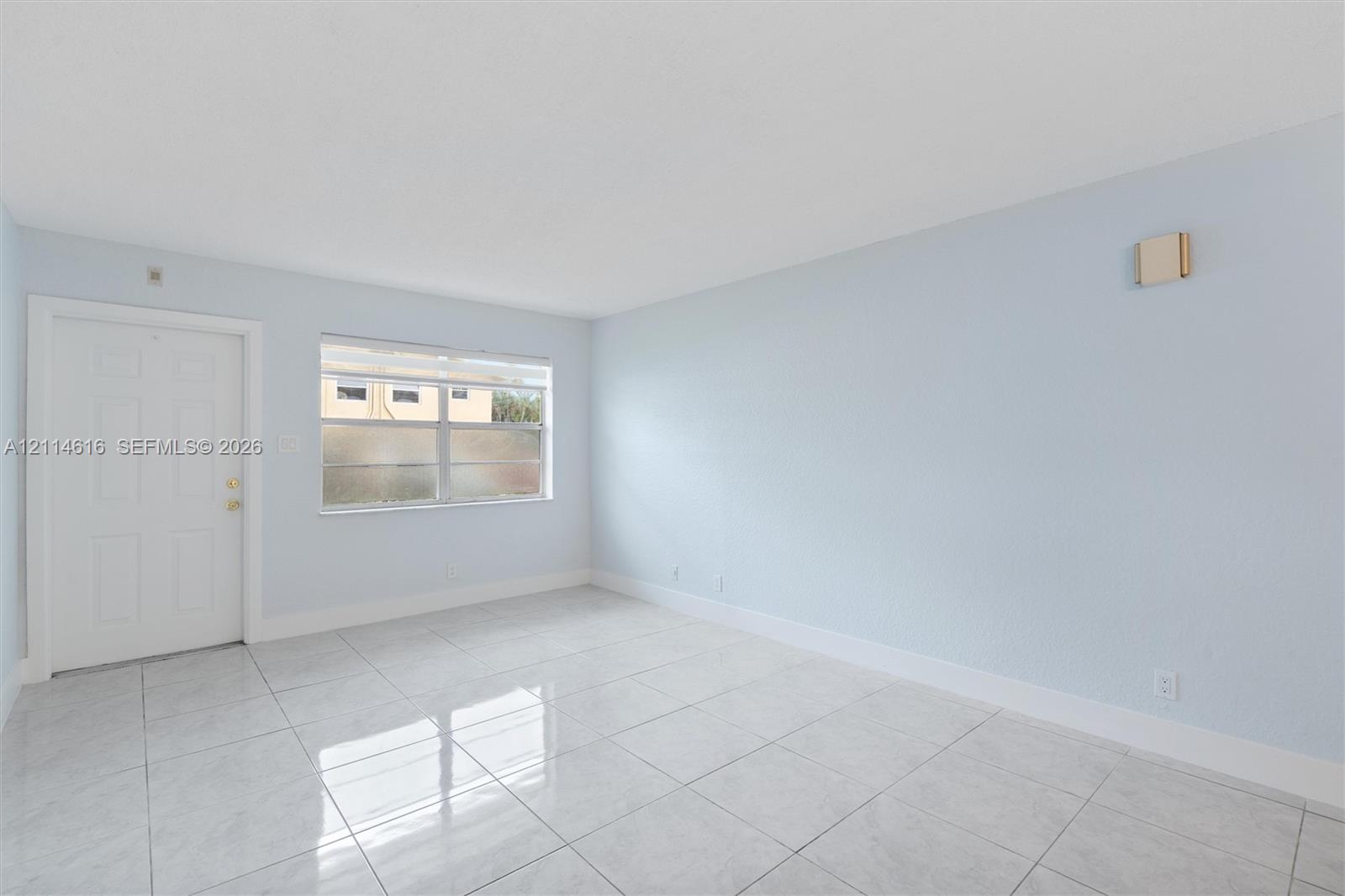 Interior room featuring large-format tile flooring, light-toned wall paint, a six-panel exterior door, and a horizontal sliding window