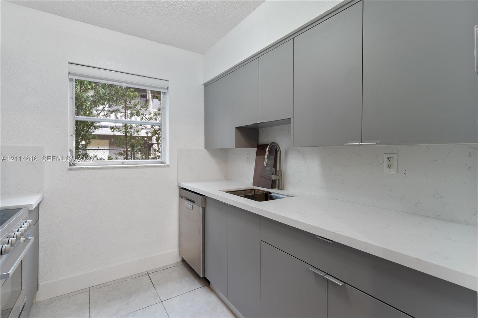 Kitchen featuring flat-panel gray cabinetry, solid-surface countertops with integrated backsplash, stainless steel dishwasher, and stainless steel pull-down faucet