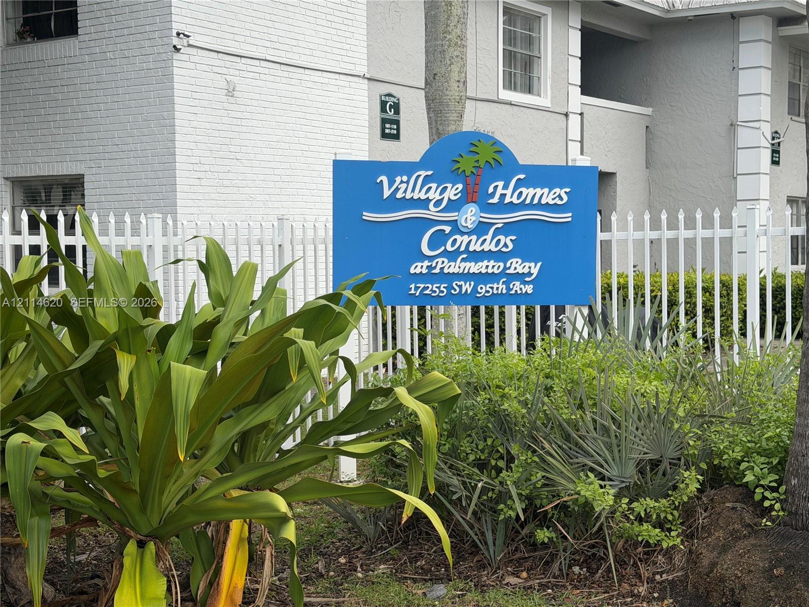 White picket fencing enclosing grounds featuring painted masonry exterior walls and established tropical landscaping