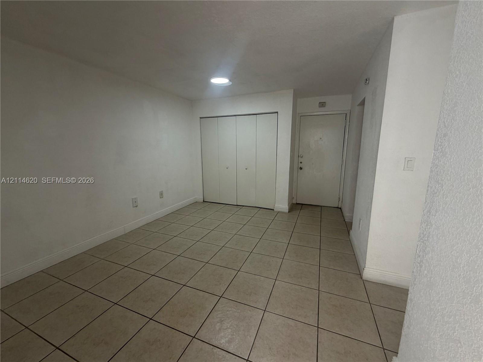 Interior space featuring neutral tile flooring, recessed ceiling lighting, and a multi-panel closet door