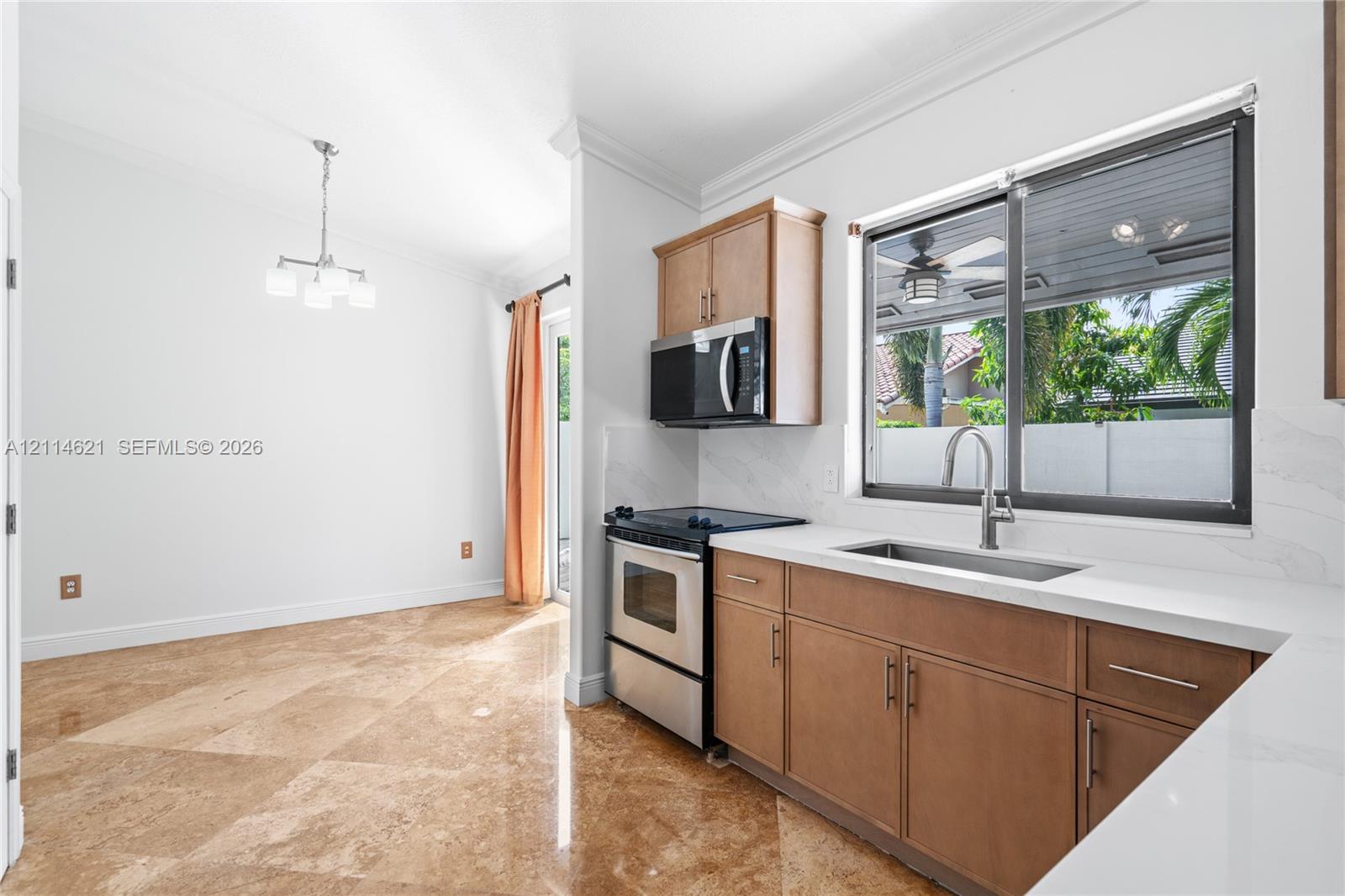 Kitchen featuring stone tile flooring, flat-panel wood cabinetry, quartz countertops, stainless steel appliances, and a stainless steel undermount sink with a gooseneck faucet