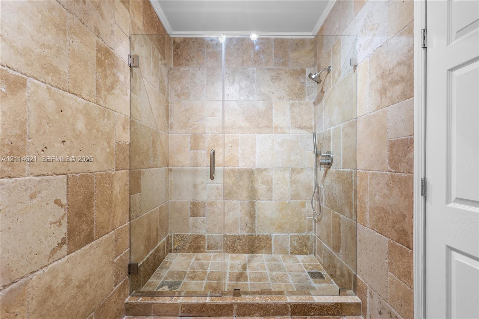 Walk-in shower featuring natural stone tile surround, frameless glass door, handheld shower head, and recessed ceiling lighting Walk-in shower featuring natural stone tile surround, frameless glass door, handheld shower head, and recessed ceiling lighting