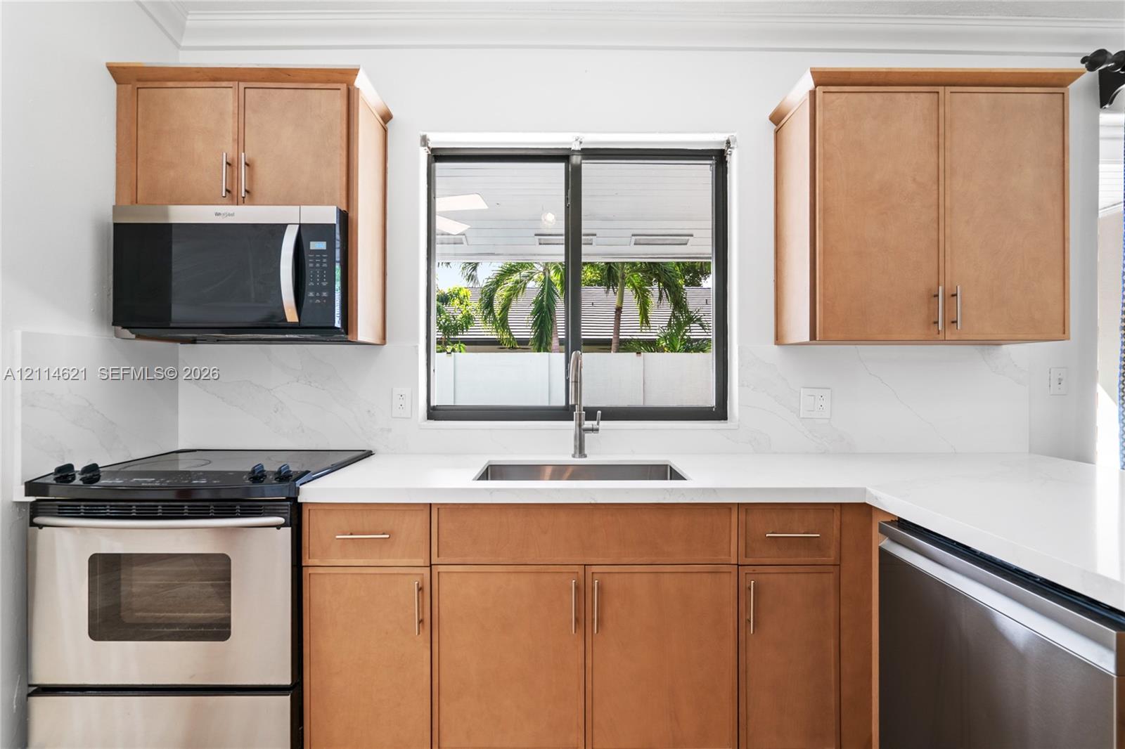 Kitchen featuring wood-finish cabinetry, solid surface countertops, a stainless steel undermount sink, matching stainless steel appliances, and a single-handle pull-down faucet