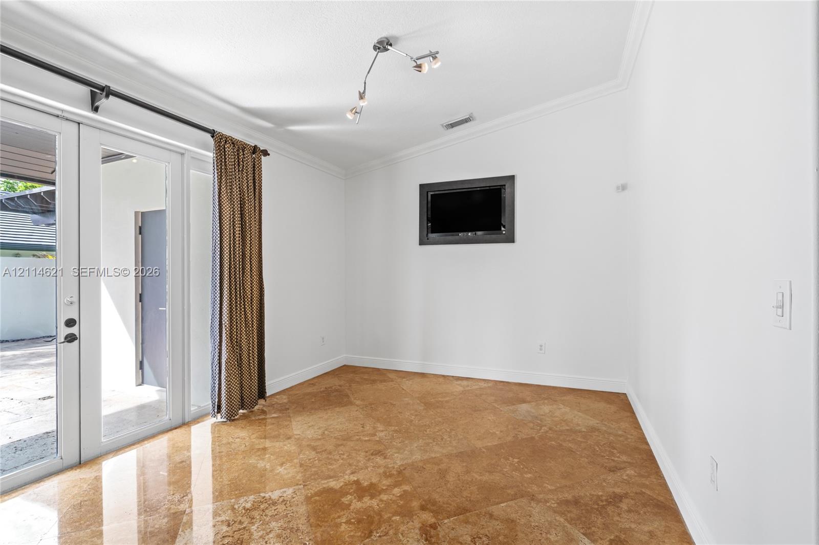 Polished stone flooring, crown molding, multi-light ceiling fixture, and glass-paned double doors