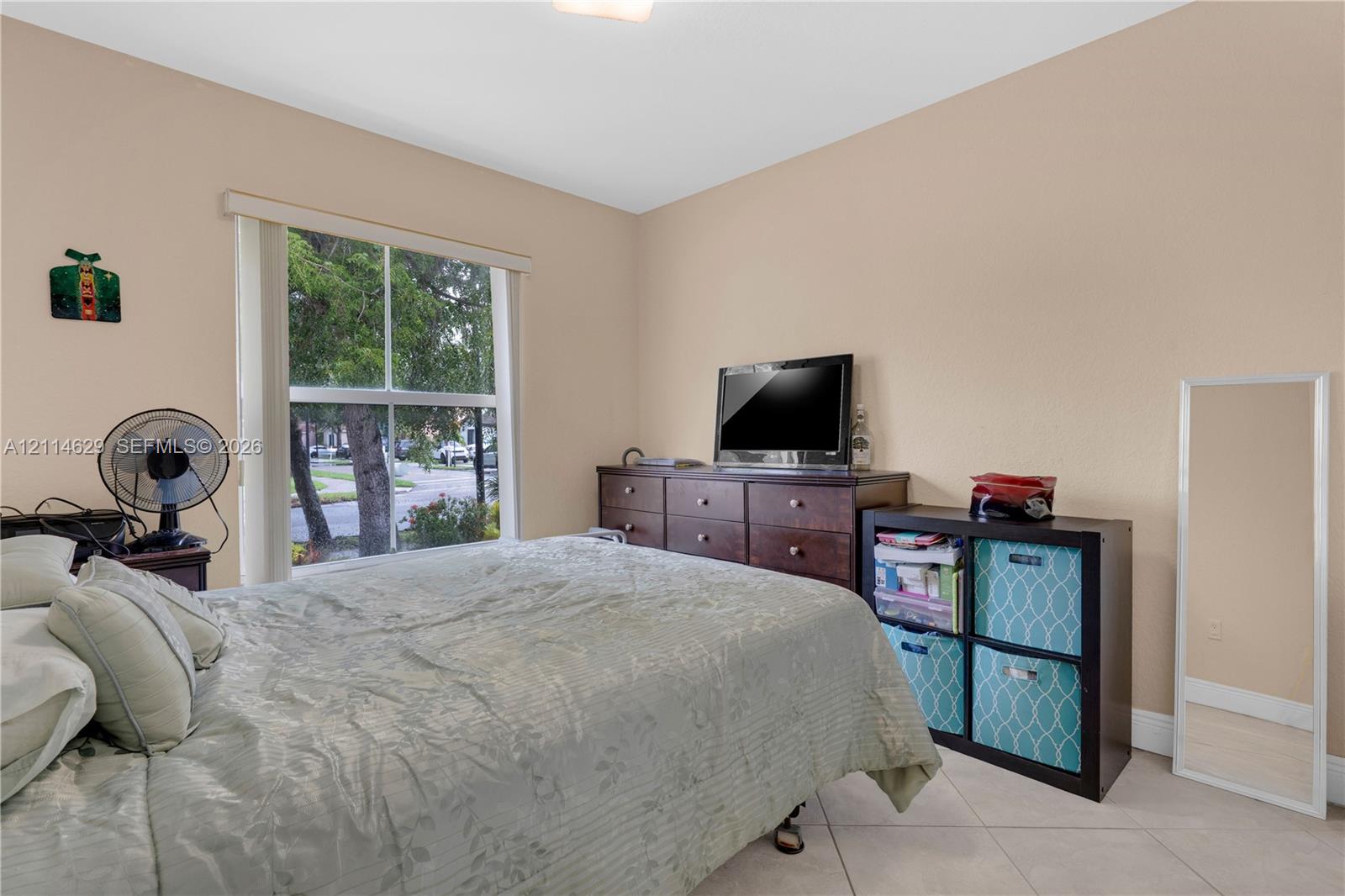 Neutral-toned interior space featuring large window with exterior glass pane, tile flooring, and overhead lighting