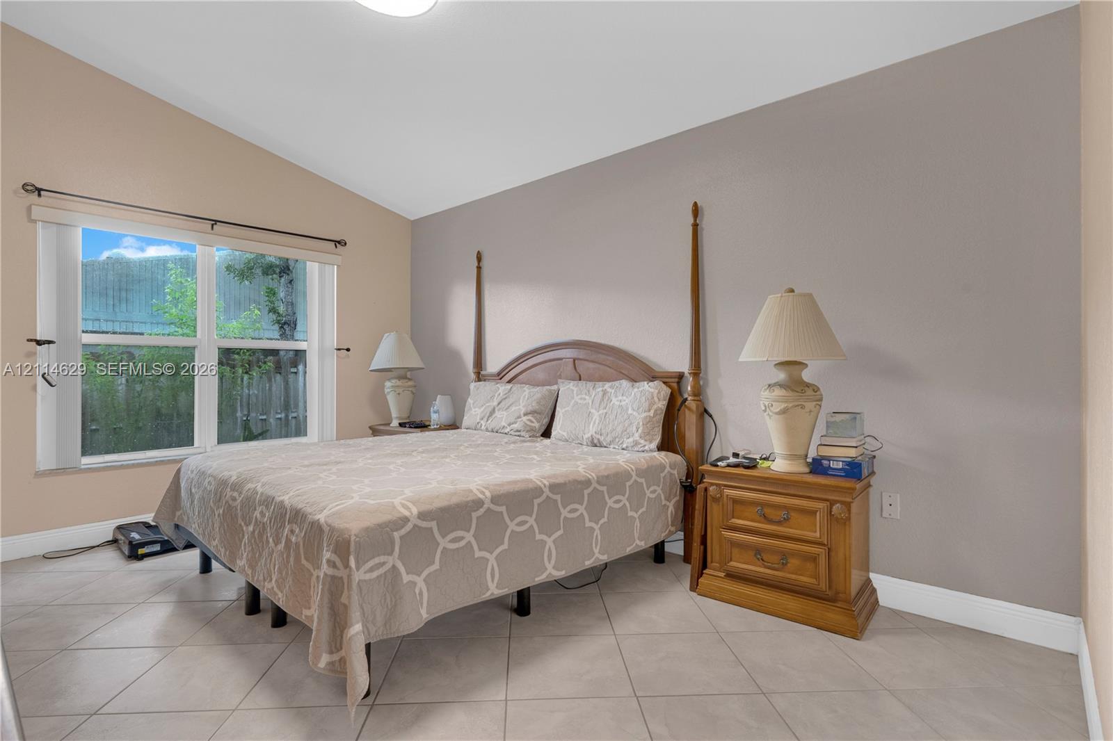 Room featuring vaulted ceilings, neutral wall tones, large window, and light-toned ceramic tile flooring