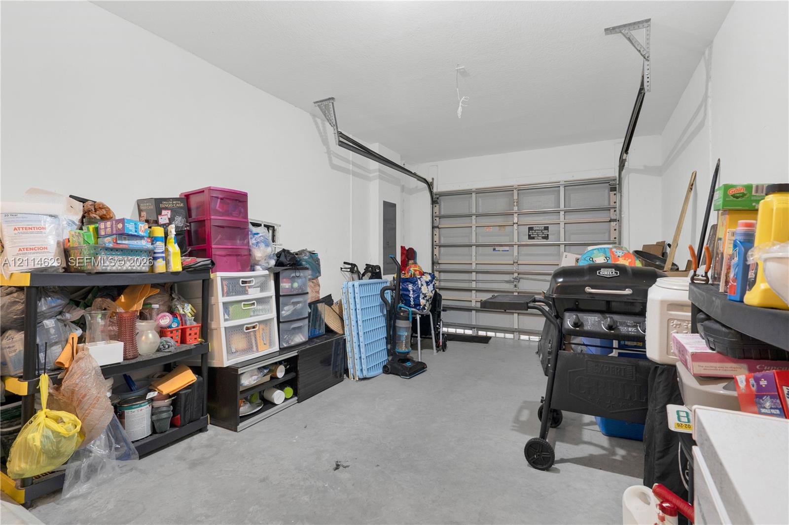 Enclosed garage featuring concrete flooring, white walls, and a sectional overhead door