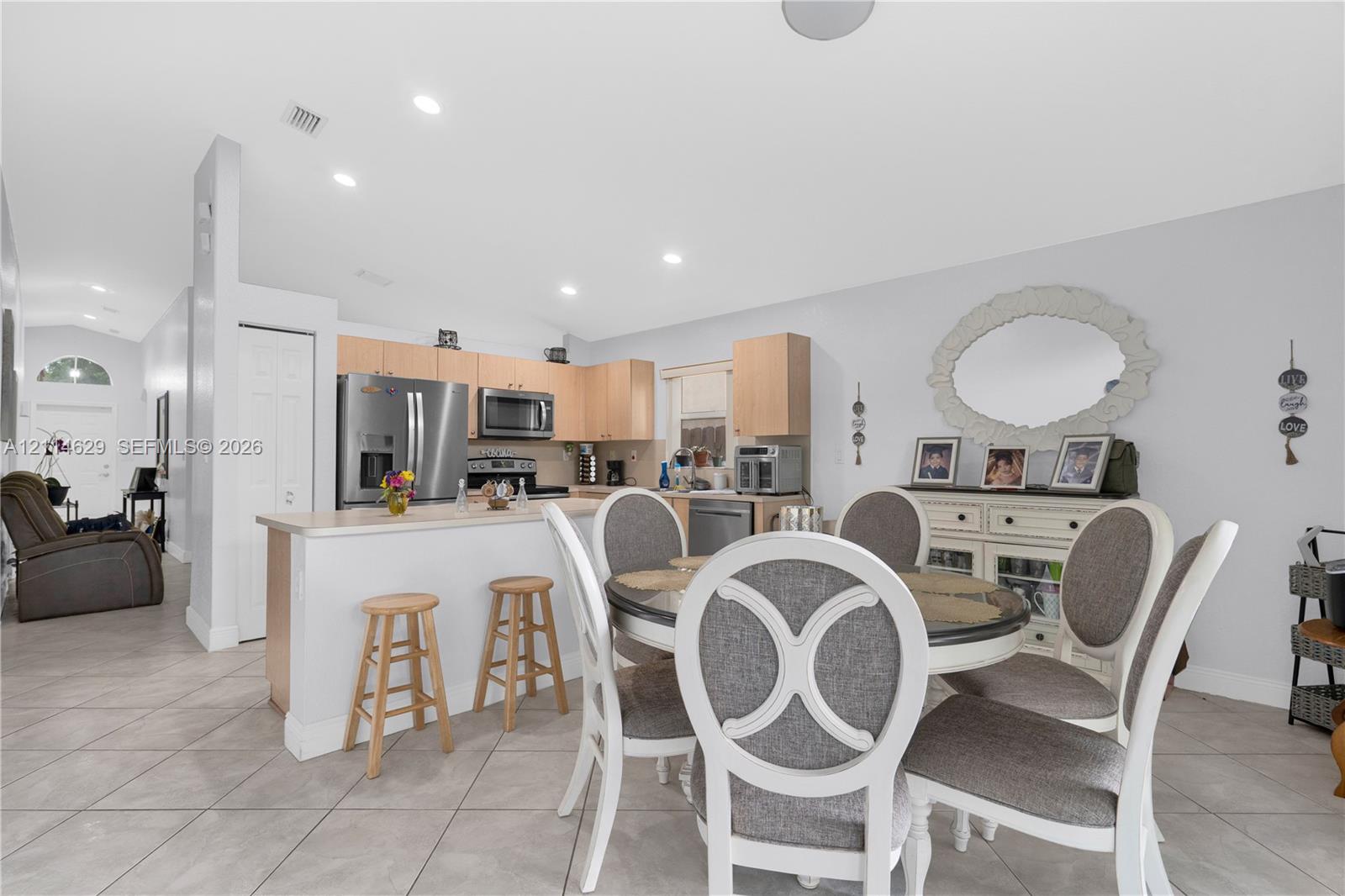 Kitchen featuring light-finish cabinetry, stainless steel appliances, a peninsula with a breakfast bar, recessed lighting, and tile flooring