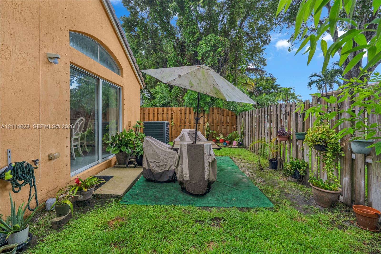 Stucco exterior featuring a sliding glass door with an arched transom window, a fenced backyard, and a concrete patio slab